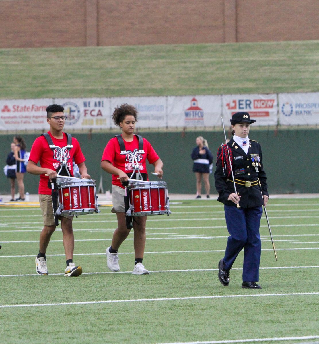Battalion commander Lorelei Mitchell (right) leads a pair of Memorial drummers onto the field before the national anthem at Friday's football game against Frenship. 