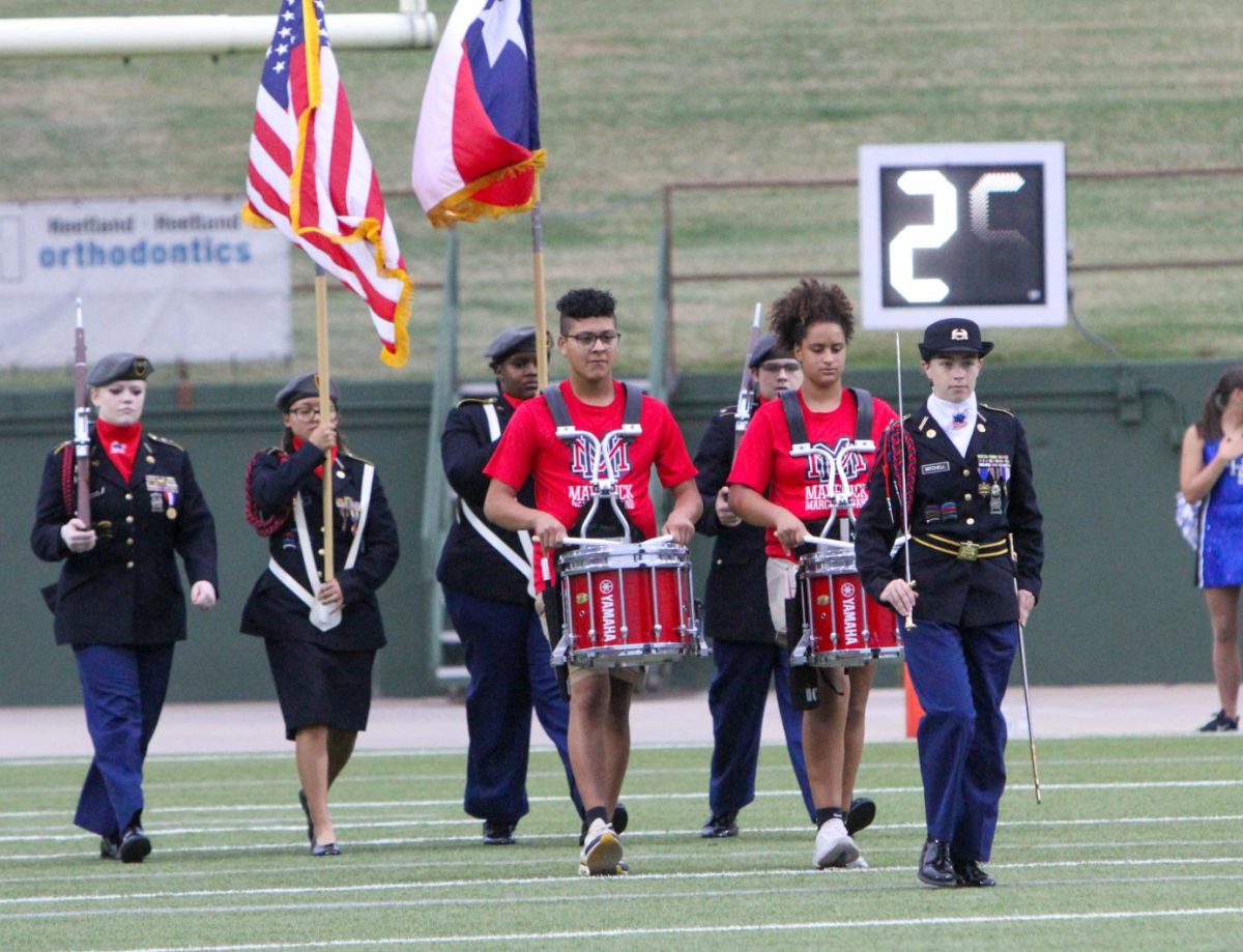 Lorelei Mitchell leads the JROTC color guard onto the field during a football game. 